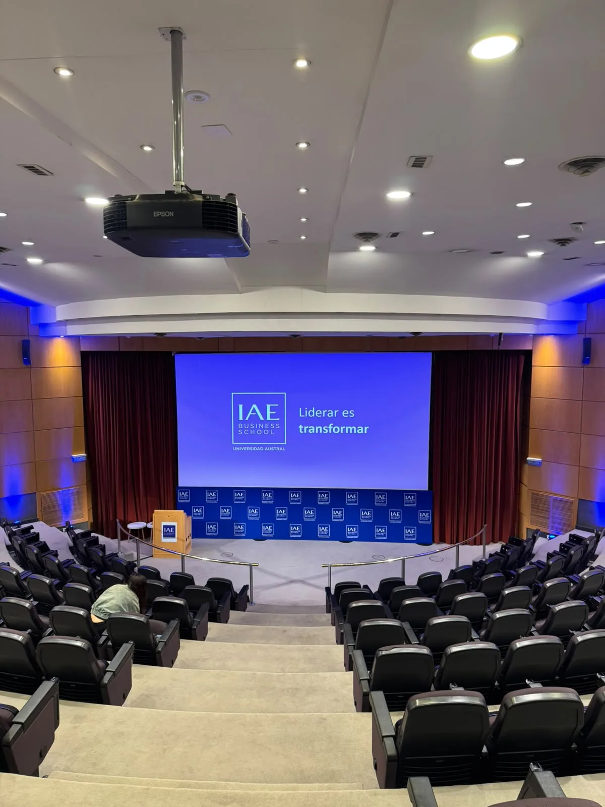 Auditorio del IAE Business School con la pantalla «Liderar es transformar»