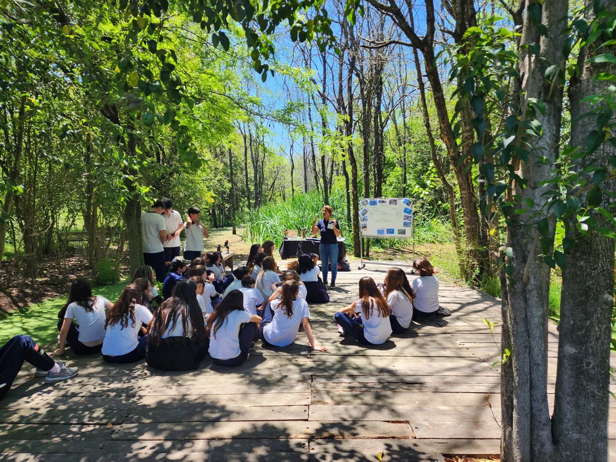 Grupo escolar escuchando a una guía en el bosque